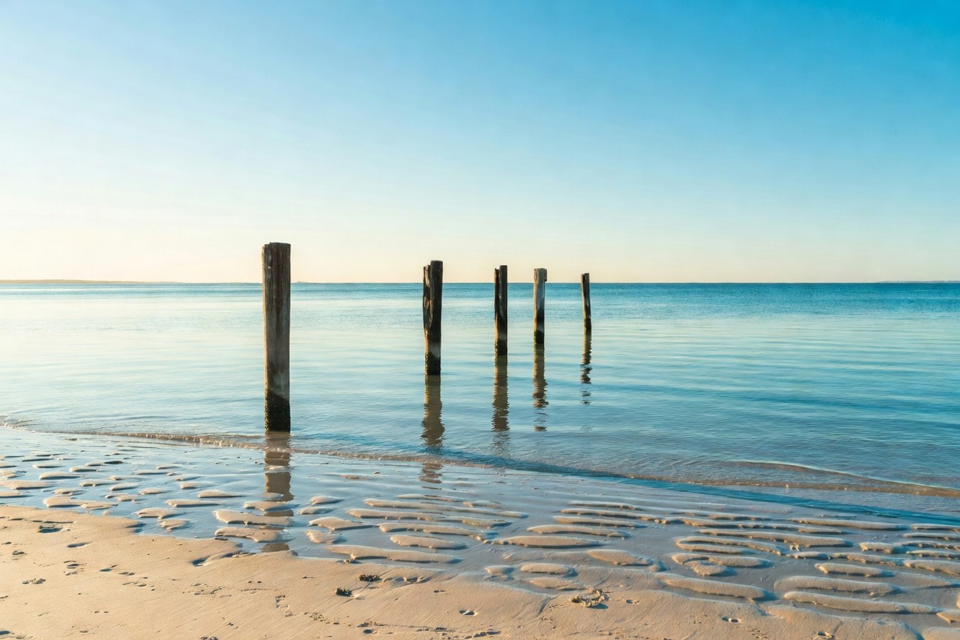 Four evenly spaced pylons stretching into calm coastal water, symbolising the repeatable quarterly cycle of pre-qualification rounds rather than a single tender deadline.